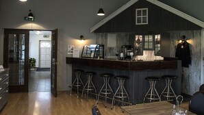 A bar area with stools, a counter, and a wooden wall. There are hanging lights and a door in the background. - Dalakot (Budardalur)