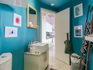 A bathroom with a sink, toilet, and mirror. There are framed pictures on the wall and a towel rack with towels. - Designer De Waterkant Pad (Cape Town)