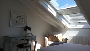 Una habitación con tragaluz, una cama, un escritorio y una silla.