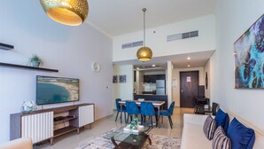 Una sala de estar moderna con una televisión de pantalla plana, un sofá, una mesa de centro y un comedor con sillas.