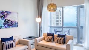 Una sala de estar moderna con un sofá, una mesa de centro de vidrio y vistas de la ciudad a través de amplios ventanales.