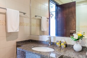 Une salle de bain avec un lavabo doté d’un plan de travail en granit, un miroir et deux serviettes suspendues à un porte-serviettes.