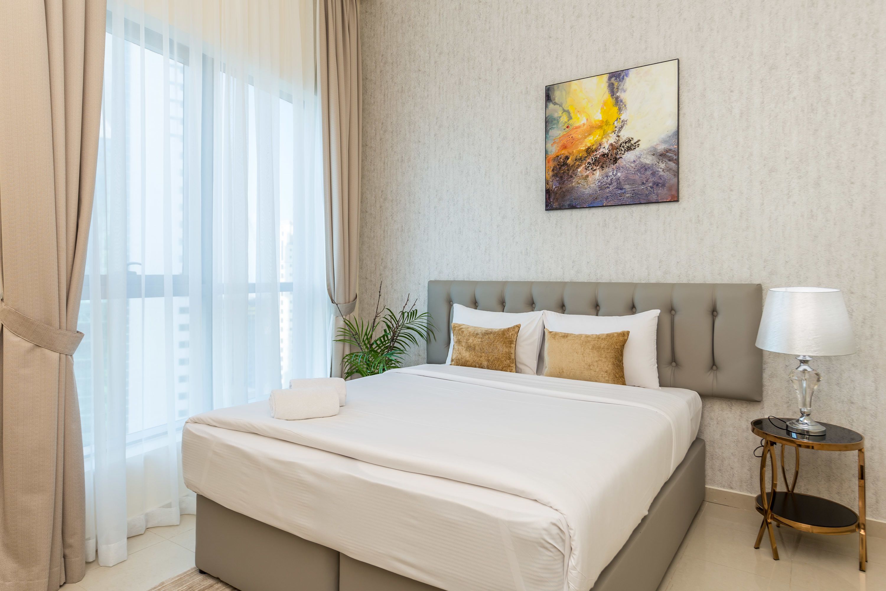 Une chambre d’hôtel moderne avec un grand lit, une table de chevet avec une lampe et un tableau au mur.