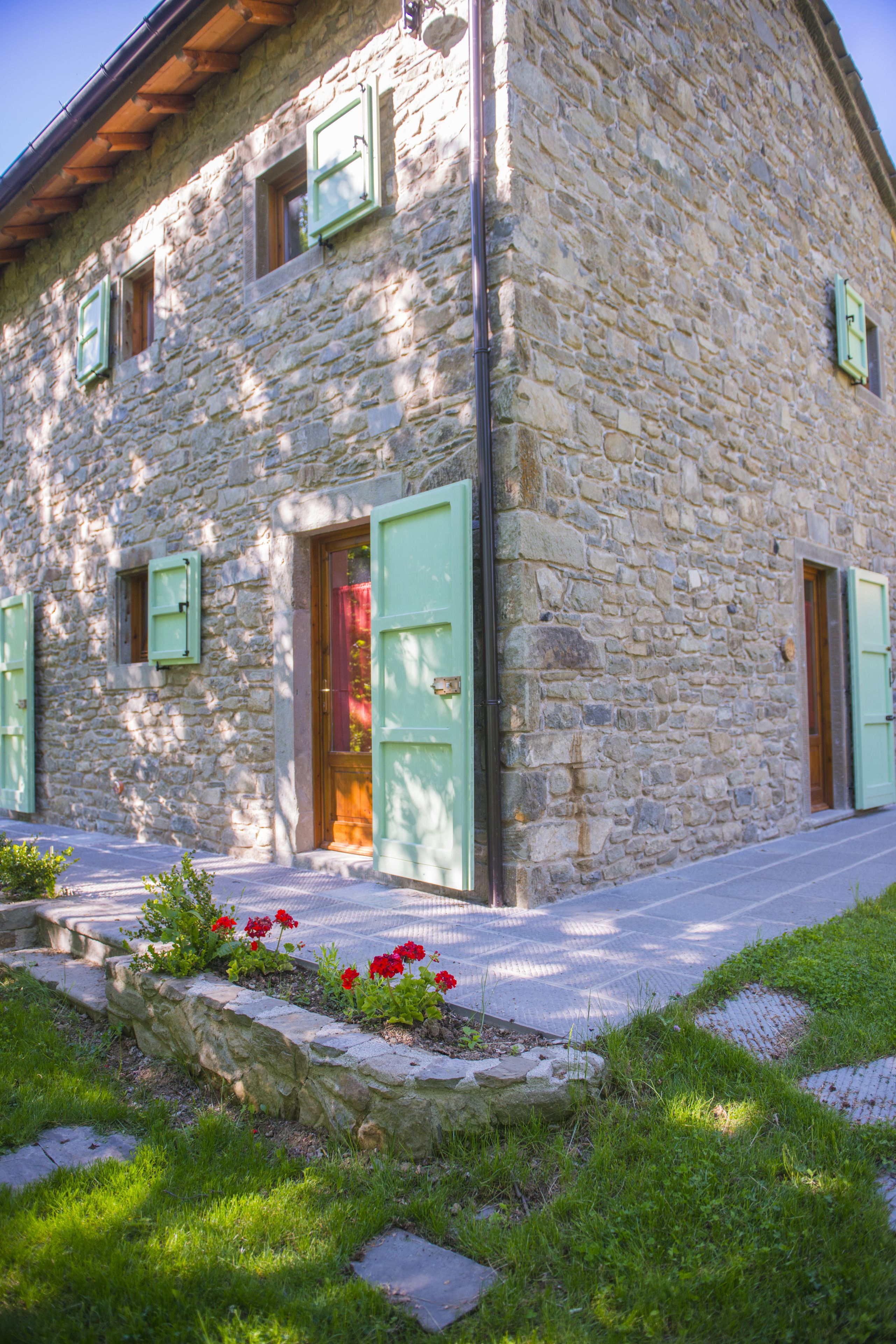 A stone building with green shutters and a wooden door.