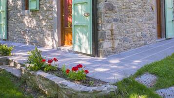 A stone building with green shutters and a wooden door.