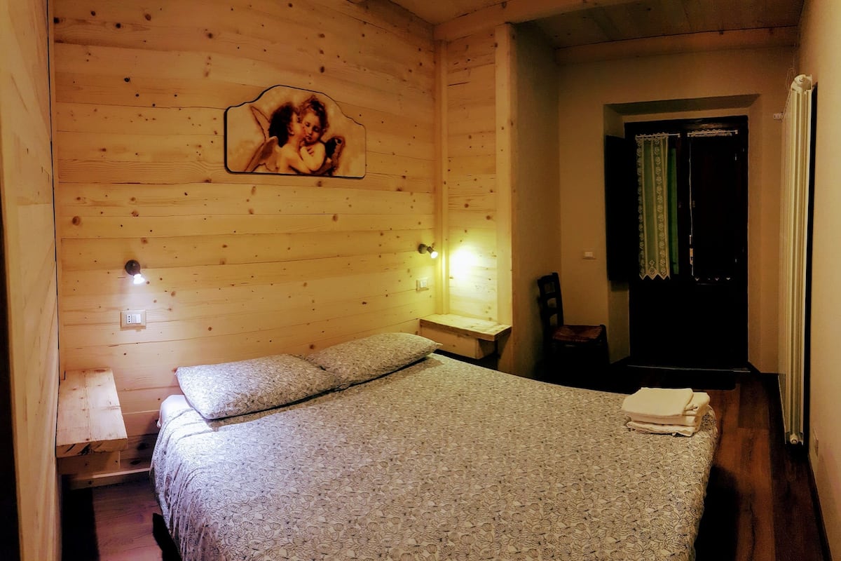 Une chambre à coucher aux murs lambrissés, avec un lit, une table de chevet, une lampe et un tableau encadré accroché au mur.