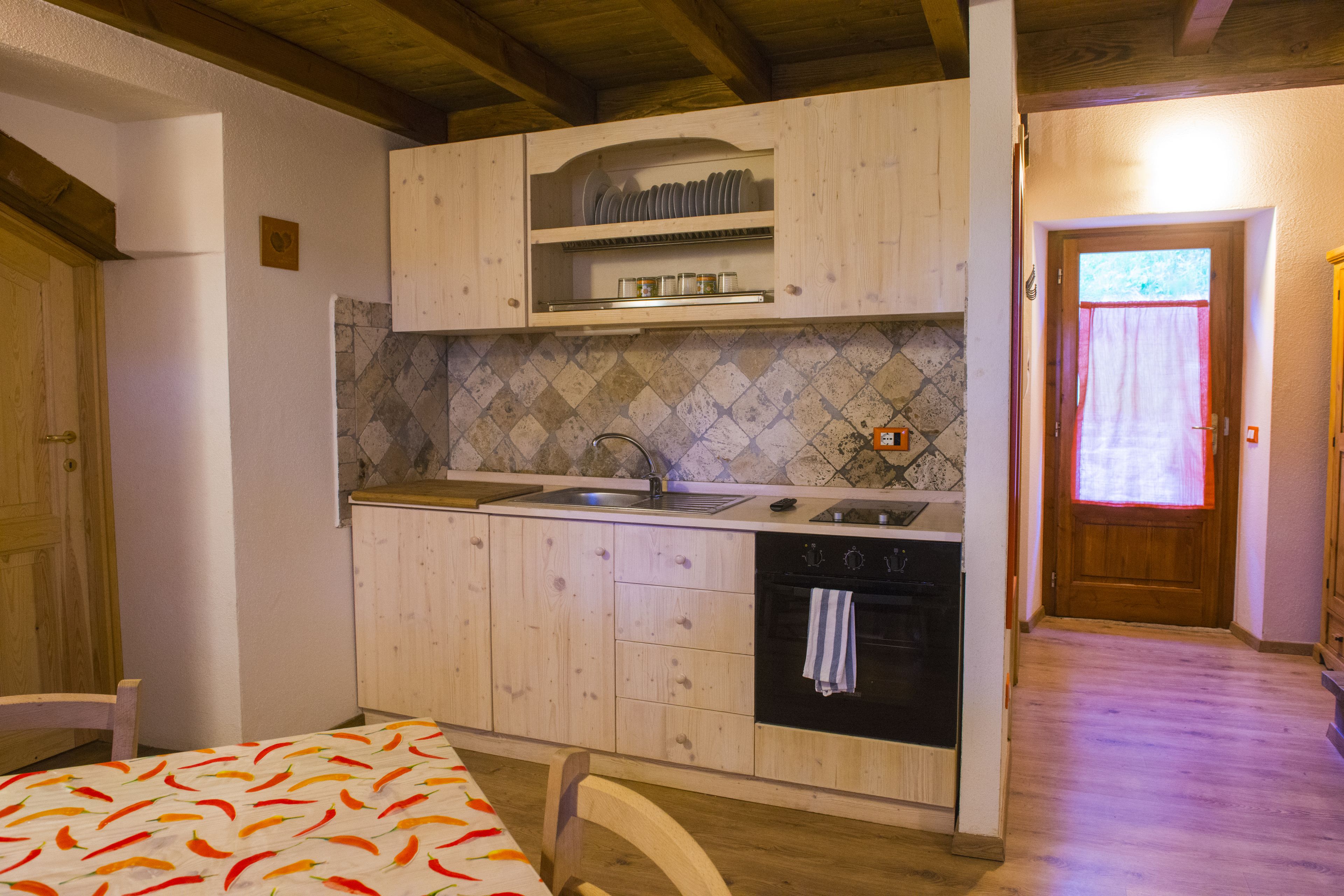 Une cuisine compacte avec des meubles en bois, un pare-feu en carrelage et un four encastré.