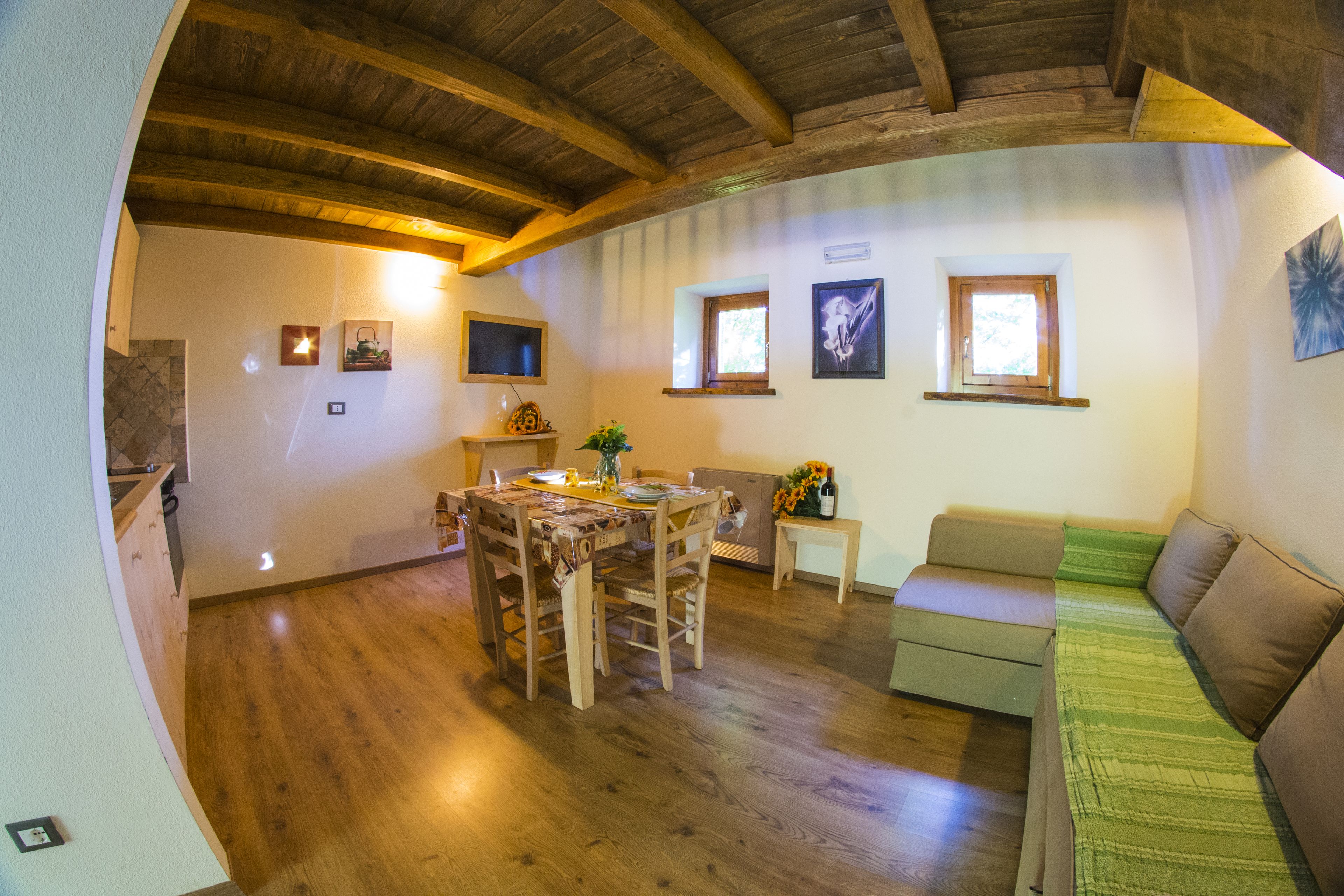 A dining area with a wooden table and chairs, a sofa, and a small window.