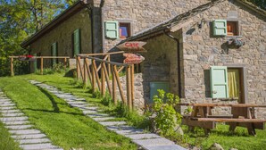 Un bâtiment en pierre avec un chemin de pierre menant à un banc en bois.