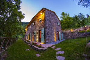 Una casa de piedra con varias puertas y ventanas, rodeada de un jardín cuidado y una valla de madera.