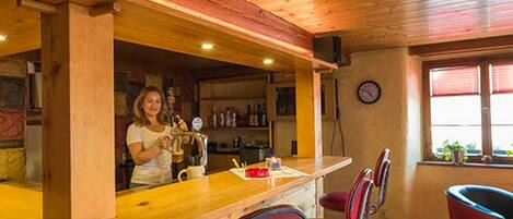 A bar area with wooden ceiling and red bar stools.