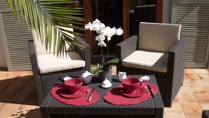 Een eettafel met twee rode placemats, witte bekers en een potorkidee.
