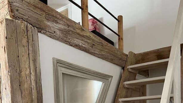 Een houten trap met een witte leuning en een deur met een geëtste glazen ruit.