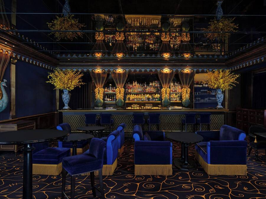 Un área de bar con diversas opciones de asientos, barra y elementos decorativos como jarrones y plantas.