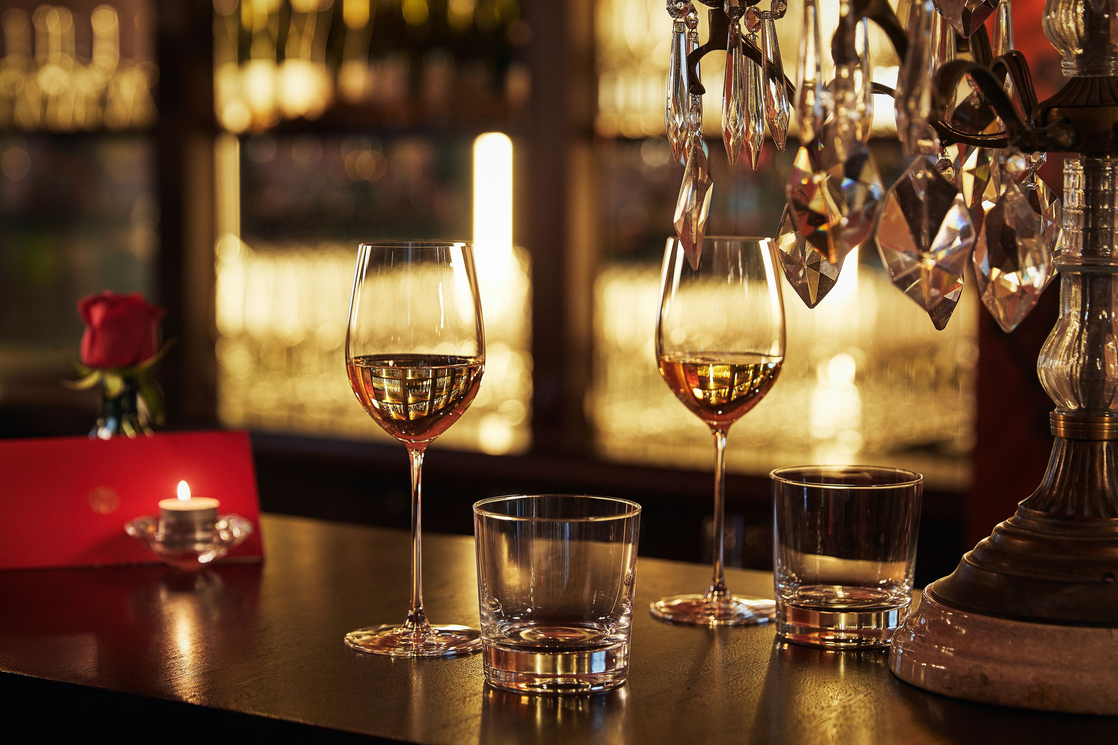 A bar setting with glasses of wine, a candle, and a decorative metal piece.