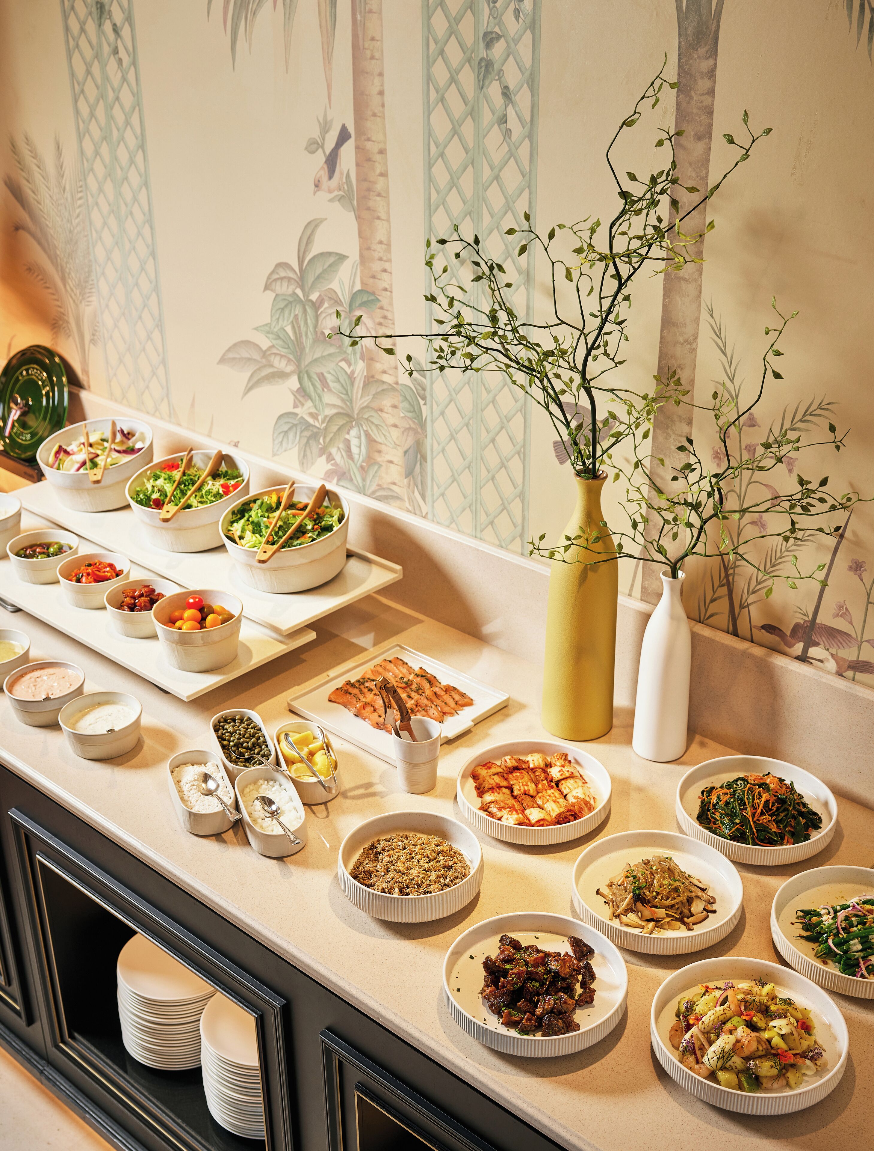 A buffet table with various dishes and a decorative plant.