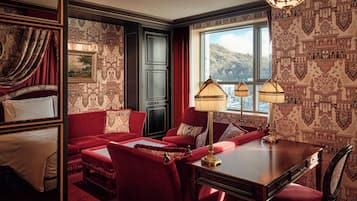 Une pièce avec un canapé rouge, une table en bois et une vue sur un paysage montagneux par la fenêtre.