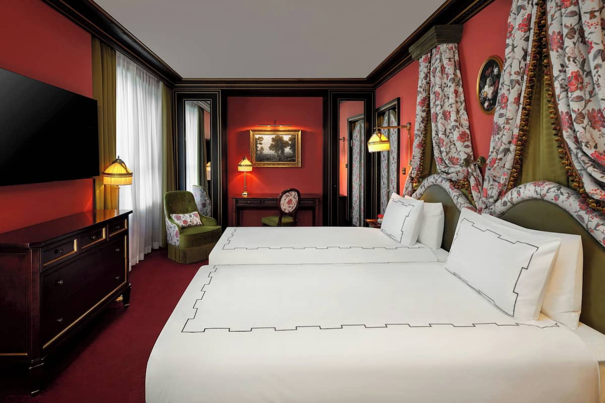 A hotel room with a large bed, a dresser, a chair, a desk, and a television.