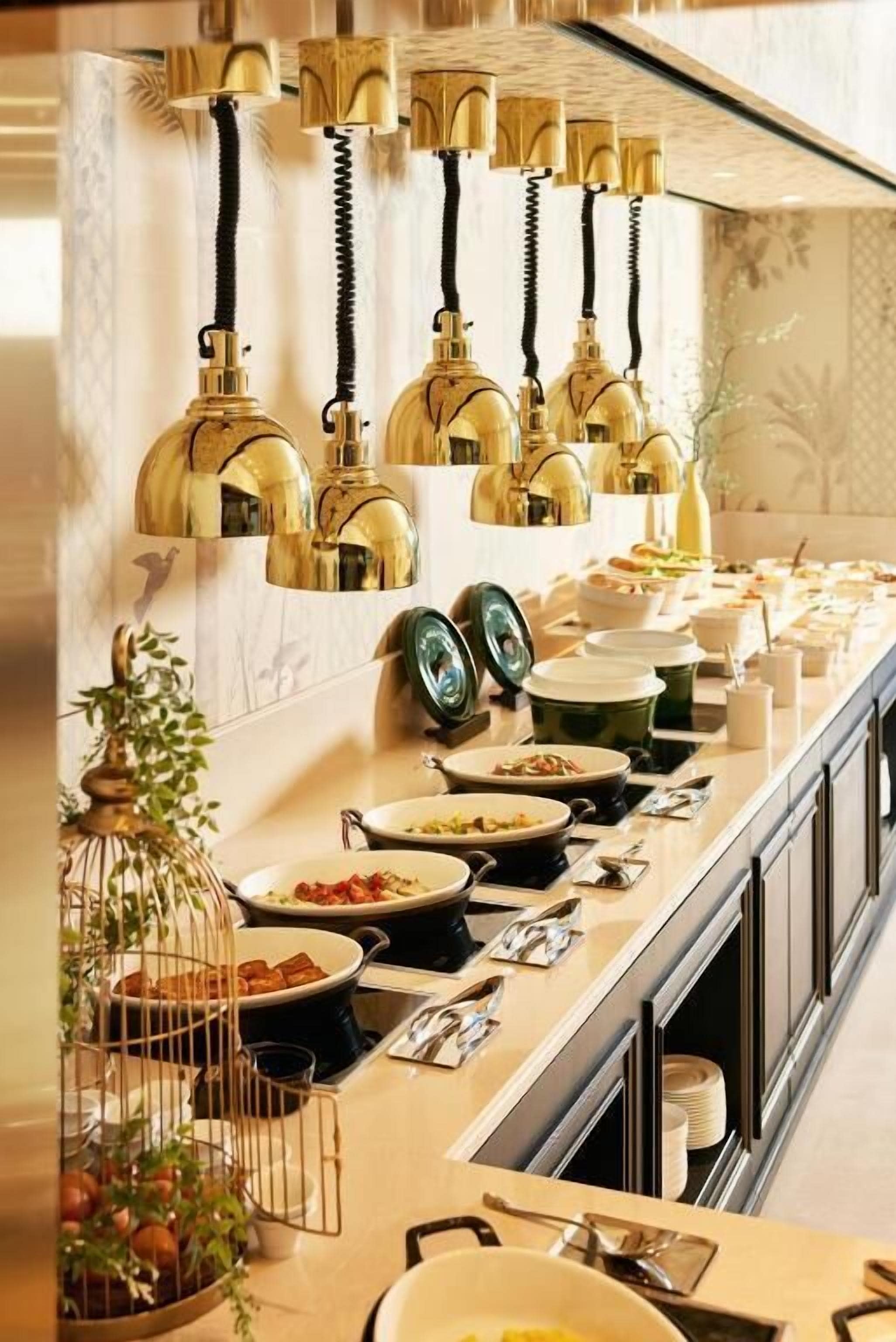 A buffet setup with multiple serving stations, a variety of dishes, and decorative lighting.