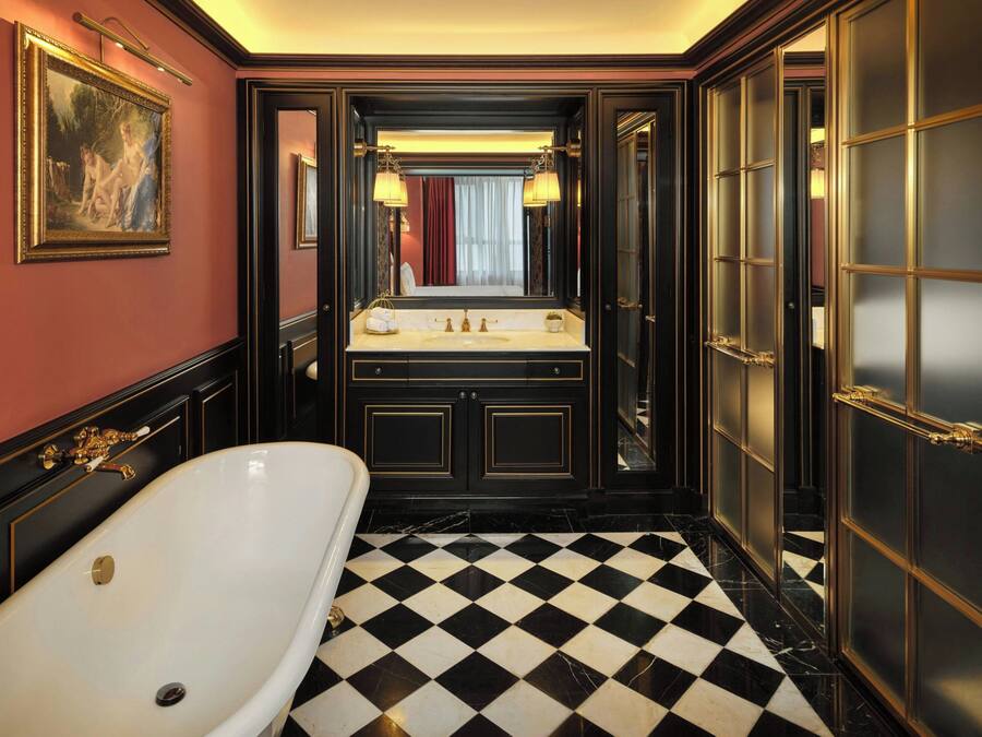 A luxurious bathroom with a large bathtub, a vanity with a mirror, and a checkered floor.