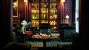 A library with bookshelves, a round table with plates and glasses, and two chairs. - L’Escape, a Luxury Collection Hotel, Seoul Myeongdong (Seoul)