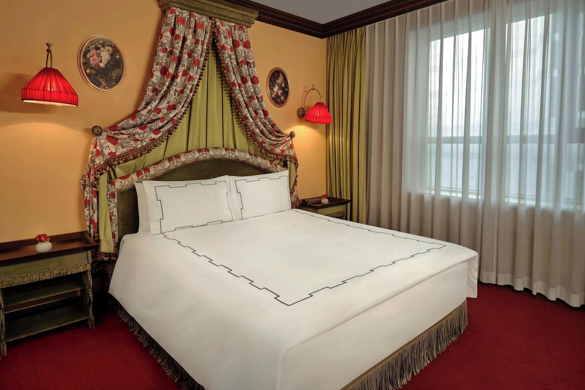 A neatly made bed with a headboard, two bedside tables, and a window with curtains.