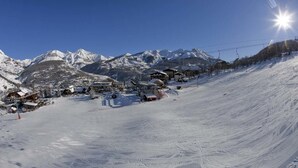 A snow-covered ski slope with buildings and a ski lift. - Hôtel Franz (Allos)