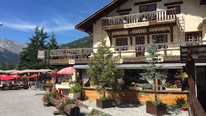 A traditional chalet-style building with a sign reading "HOTEL FRANZ" and a "BAR" sign below. - Hôtel Franz (Allos)