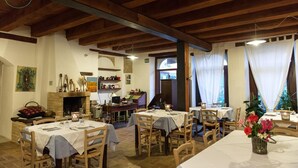 A restaurant with wooden beams, white walls, and tables set for dining. - Agriturismo Bassarì (Recanati)