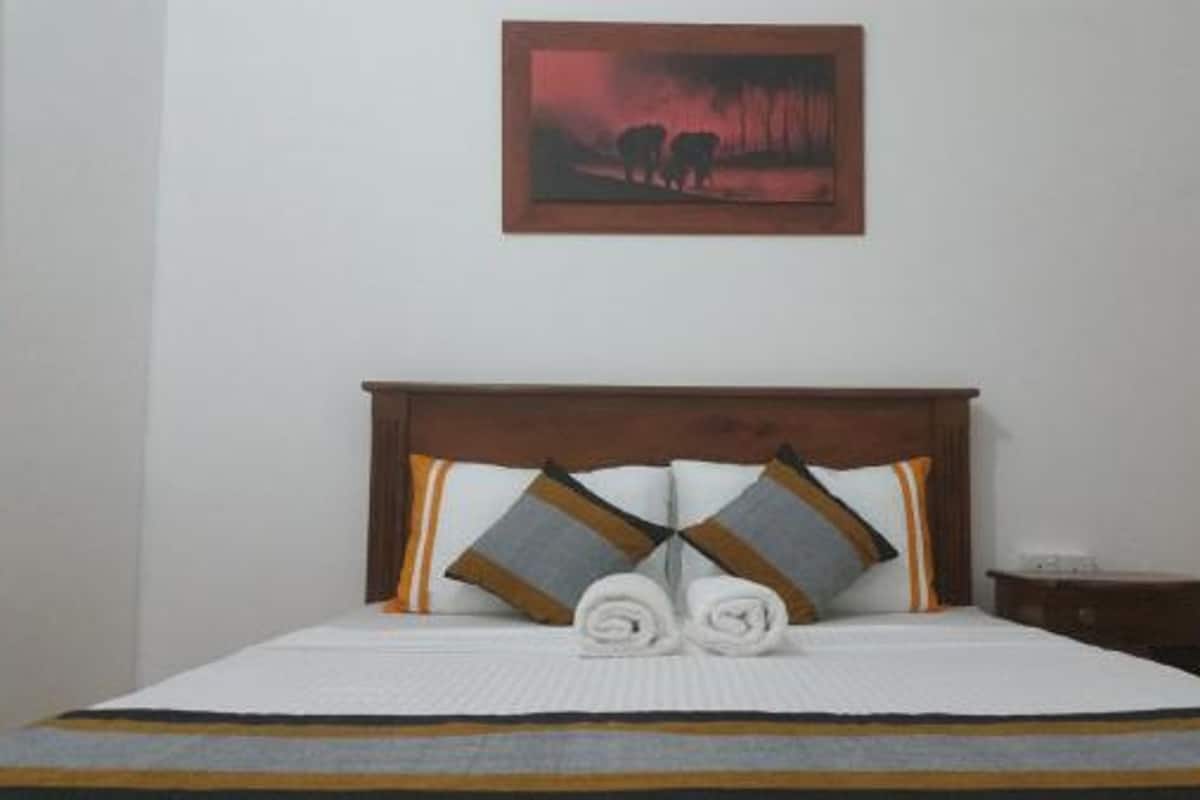 A bed with a wooden headboard, two pillows, and two rolled towels.
