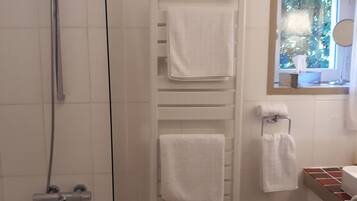 A bathroom with a shower, a toilet, a sink, and a window with a view of trees.