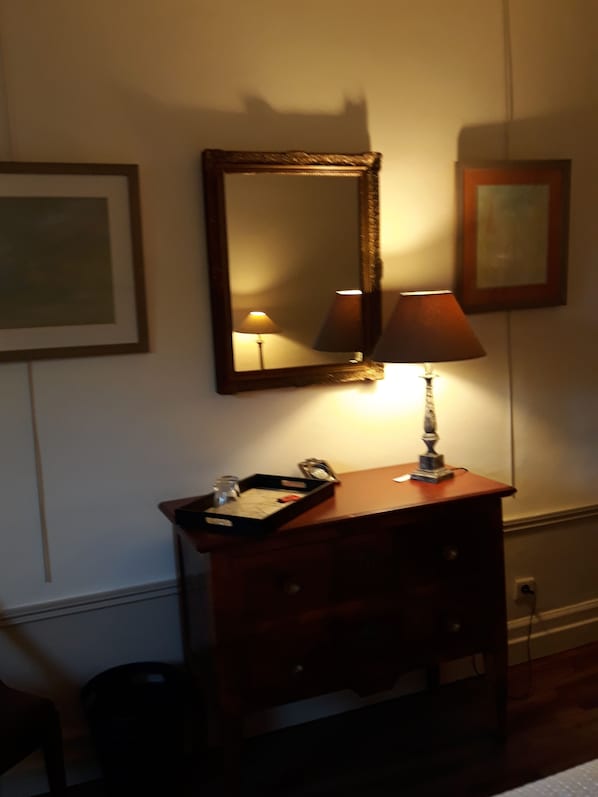A wooden dresser with a mirror, a lamp, and a tray with a glass and a book. - La Maison Epellius (Collonges-au-Mont-d'Or)