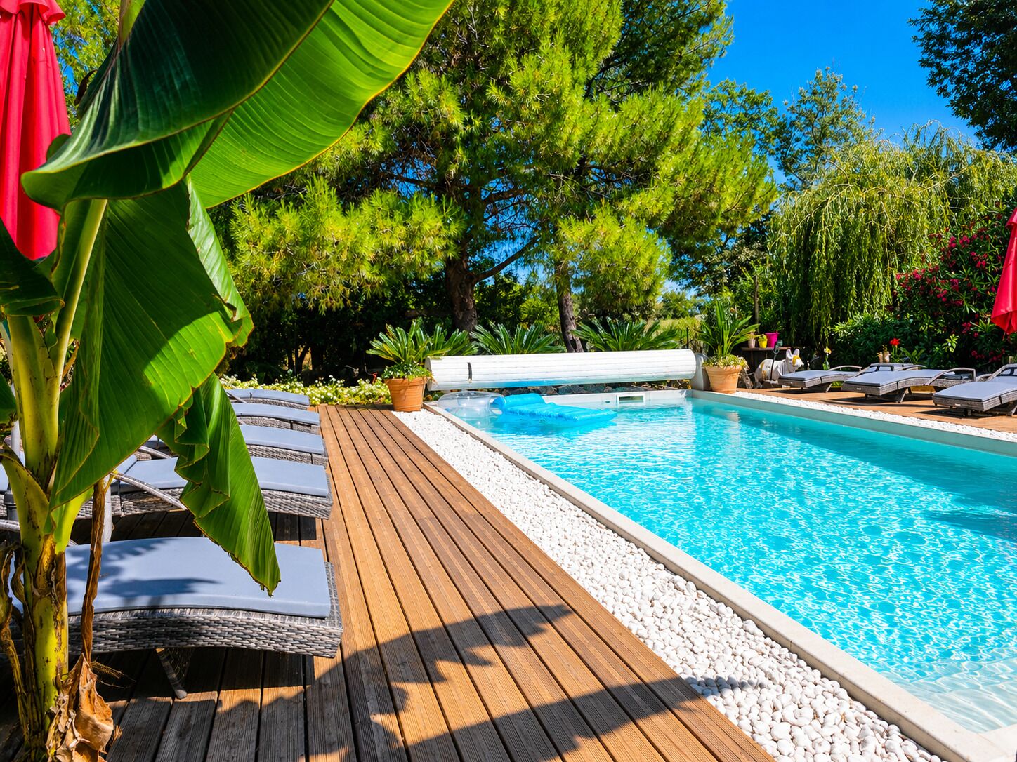 A poolside area with lounge chairs, a wooden deck, and a pool.