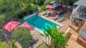 A swimming pool surrounded by lounge chairs and umbrellas, with a patio area and a hot tub. - Villa Alyzea (Bessan)