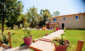 A house with a pool, potted plants, and a wooden deck.