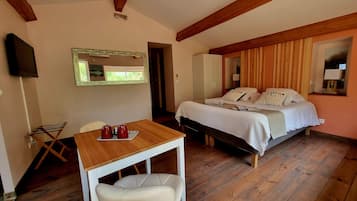 Un dormitorio con cama, una mesita de noche con dos tazas, una silla y un televisor montado en la pared.