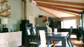 A dining area with a table, chairs, and a cabinet. There is a wall-mounted mirror and an air conditioning unit. - Villa Alyzea (Bessan)