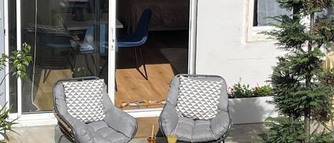 A patio with two grey chairs, a small table, and a potted plant.