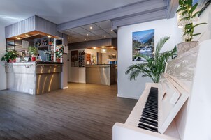 Un salón espacioso con cocina, piano y comedor.