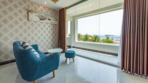 Ein modernes Zimmer mit einem großen Fenster, einem blauen Sessel, einem kleinen runden Tisch und einer Wand mit Muster.