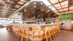 Eine Bar mit hölzernen Barhocker, einer Bar und einer grünen Wanddekoration.