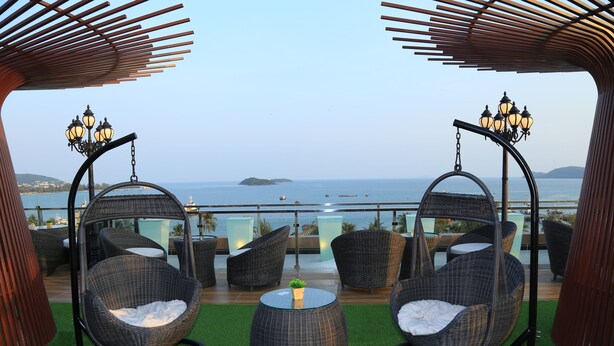 Eine Terrasse mit Korbstühlen, einem kleinen Tisch und einer Hängematte mit Blick auf das Meer.