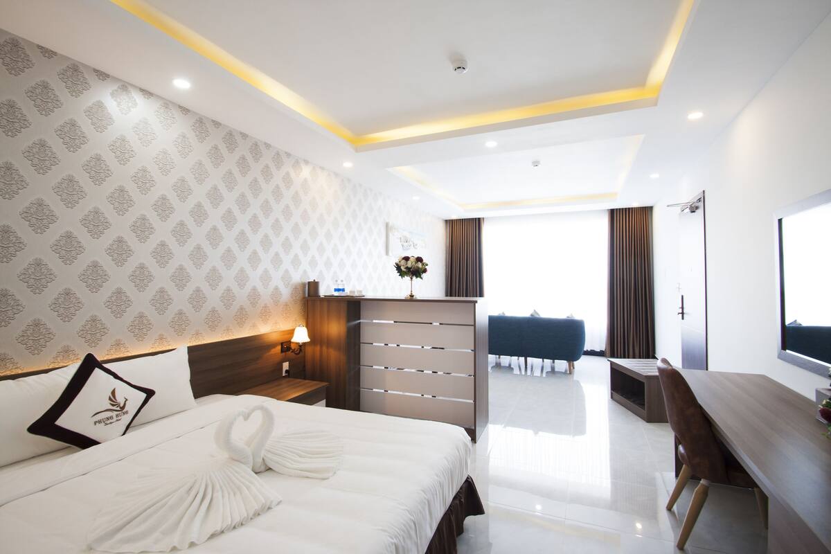 A modern hotel room with a neatly made bed, a desk, and a view of the balcony.