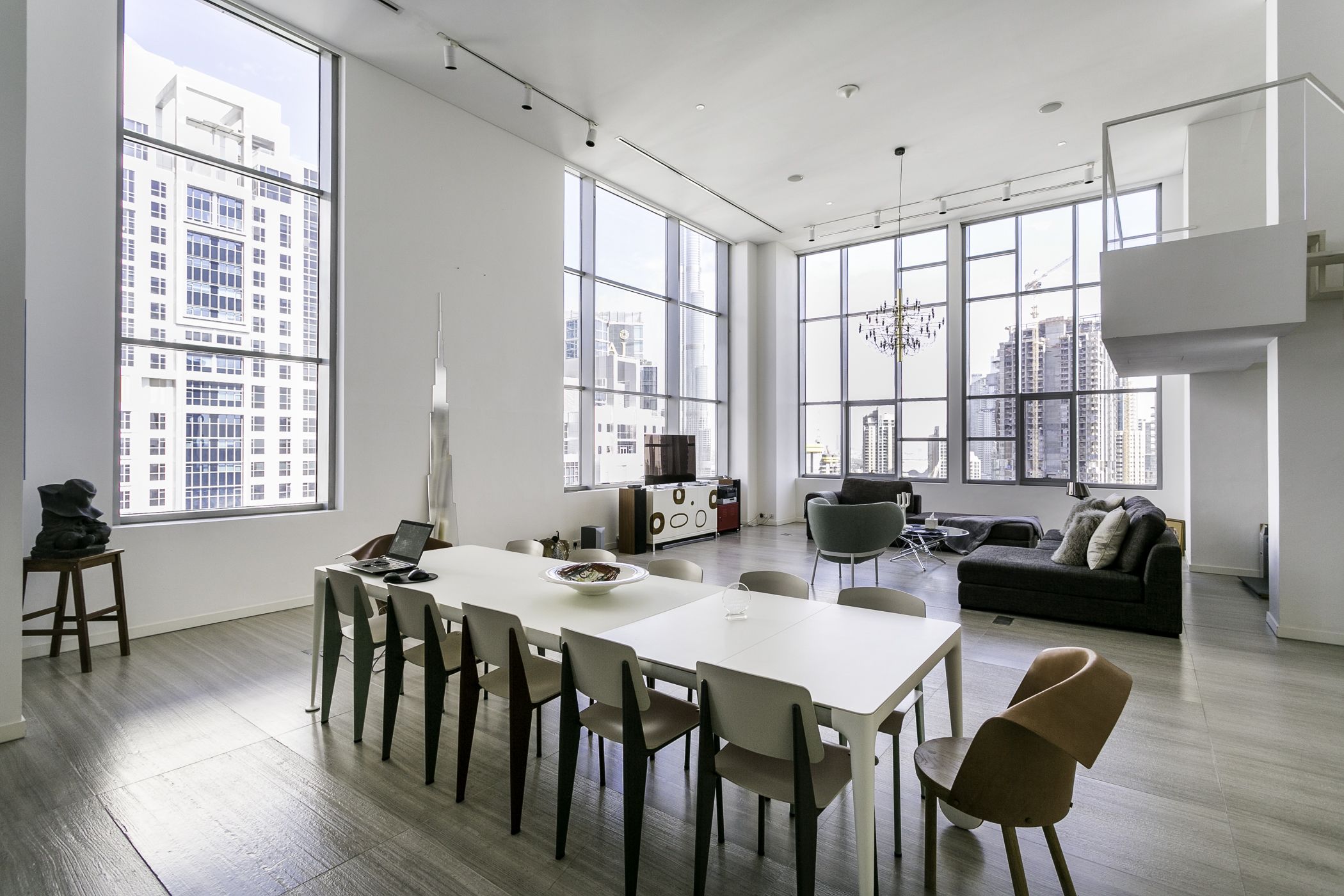 Amplia sala de estar con mesa y sillas de comedor, un sofá y grandes ventanales con vistas a la ciudad.