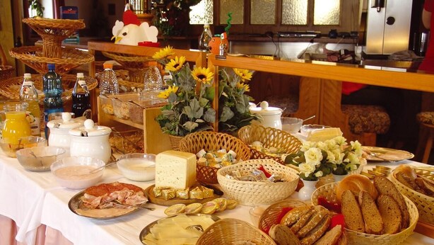 A buffet table with various food items, including bread, cheese, and pastries, arranged on a table with a white tablecloth. - Hotel Oberhofer (Rio di Pusteria)