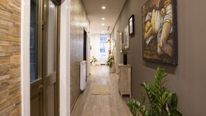 A hallway with wooden flooring, a beige carpet, and a potted plant. - Hotel Tergeste (Trieste)