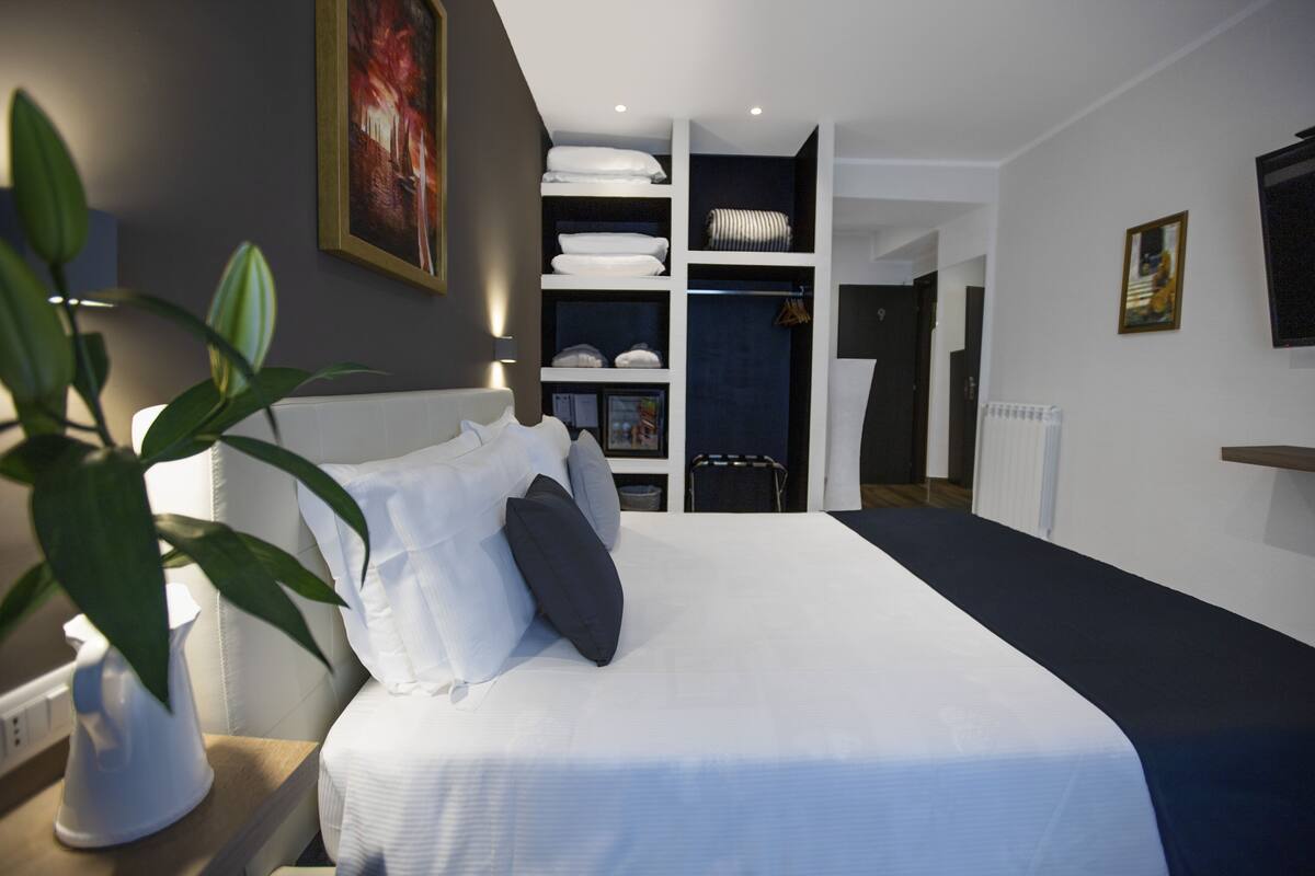 A modern bedroom with a large bed, built-in closet, and a potted plant.