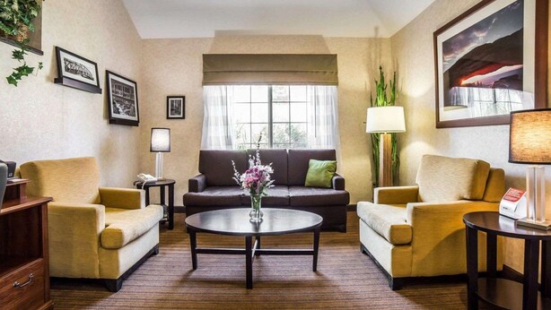 A hotel room with a sofa set, a coffee table, a lamp, and framed pictures on the walls. - Quality Inn Moab Slickrock Area (Moab)