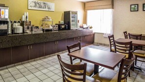 A hotel room with a kitchenette, a dining area with a table and chairs, a large window with curtains, and a wall-mounted artwork. - Quality Inn Moab Slickrock Area (Moab)
