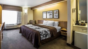 A hotel room with a bed, bedside table, lamp, and a large mirror. - Quality Inn Moab Slickrock Area (Moab)